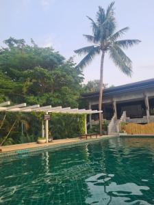 a swimming pool in front of a house with a palm tree at House by the sea in Haad Tian