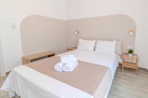 アスプロヴァルタにあるStamatia Suitesのベッドルーム1室(白いベッド1台、タオル付)