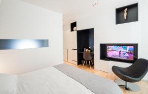 a bedroom with a bed and a chair and a television at Unique Rooms in Zadar