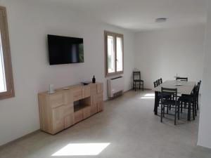 ein Wohnzimmer mit einem TV, einem Tisch und Stühlen in der Unterkunft Villa Chiara in Marina di Sorso