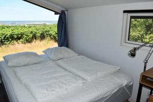 Bett mit Kissen in einem Zimmer mit Fenster in der Unterkunft Holiday home with panoramic ocean view near Kerteminde in Martofte