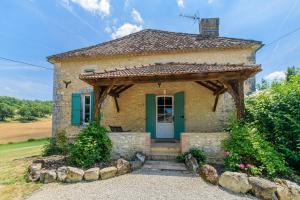 una pequeña casa de piedra con una puerta verde en La Maison de Beaugas - Avec piscine dans le pays des bastides, en Beaugas
