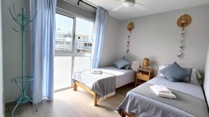a bedroom with two beds and a large window at Amplio y cómodo apartamento. in Granadilla de Abona