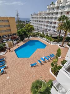 a large swimming pool with lounge chairs and a hotel at Hideaway Tenerife Holiday Apartment Las Américas in Playa Fañabe