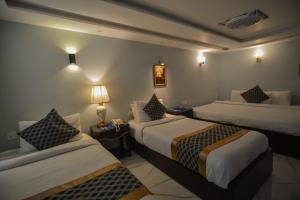 a hotel room with two beds and a lamp at Swisstel Cottage in Karachi