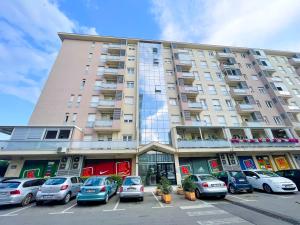 ein großes Gebäude mit Autos auf einem Parkplatz in der Unterkunft 1-bedroom apartment in urban area in Podgorica
