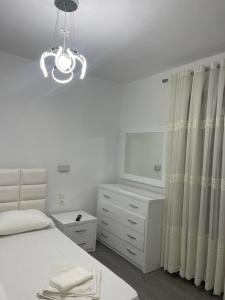 una camera con letto, cassettiera e lampadario a braccio di Ilia’s Guesthouse a Pogradec