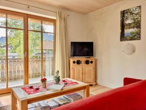 a living room with a red couch and a tv at Haus Sonnenau in Pfronten