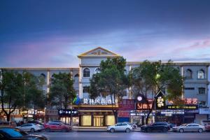 Un gran edificio con coches aparcados en un estacionamiento. en Morninginn, Lengshuijiang Yanjiang Road, en Lengshuijiang