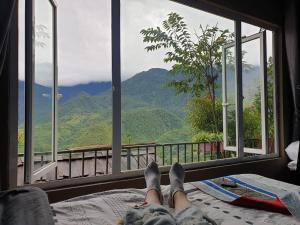 a person laying on a bed with a view of mountains at Catcat Garden House in Sapa