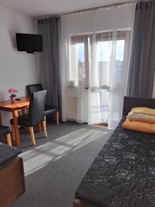 a hotel room with a bedroom with a bed and a desk at Rezydencja Kwiatano - Basen & Jacuzzi & Sauna & Plac Zabaw in Grzybowo