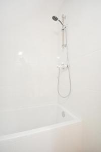 ein weißes Bad mit einer Dusche und einer Badewanne in der Unterkunft Casa con jardín en Pontevedra in Pontevedra
