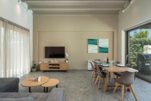a living room with a table and chairs and a tv at Ethereal Villas Chania in Daratso