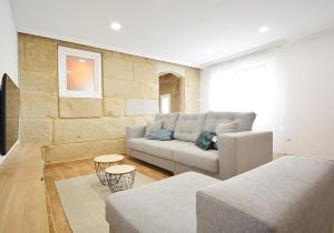 un soggiorno con divano e parete in pietra di Casa con jardín en Pontevedra a Pontevedra