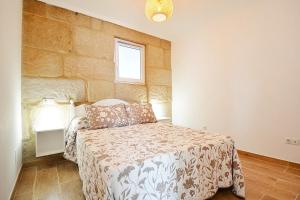 ein Schlafzimmer mit einem Bett und einer Steinmauer in der Unterkunft Casa con jardín en Pontevedra in Pontevedra