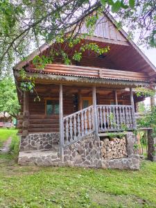a log cabin with a porch and a fence at "Бджілка" і " Садиба для відпочинку" in Lyuta