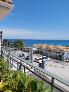 een balkon met uitzicht op een parkeerplaats en de oceaan bij Nikkos Apartments in Skála Kefalonias