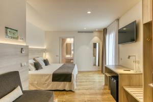 um quarto de hotel com uma cama e uma televisão em Hotel Emporium - Adults Only em Castelló d'Empúries