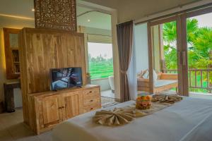 a bedroom with a bed with a television and a balcony at The Nenggala Suite in Tegalalang