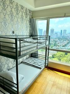 2 łóżka piętrowe w pokoju z dużym oknem w obiekcie Comfy+ by ARH KLCC w Kuala Lumpur