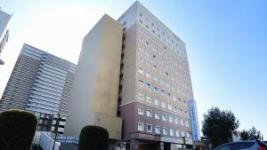 un edificio alto en una ciudad con dos edificios en Toyoko Inn Kenkyu-gakuen Ekimae, en Tsukuba