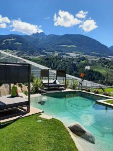 a person sitting on a bed next to a swimming pool at Apfel Chalet Feldhof in Caines