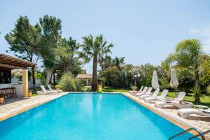 a swimming pool with chairs and umbrellas at St. George Villa in Agios Georgios