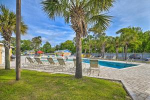 a swimming pool with chairs and a palm tree at Myrtle Beach Resort Condo - Walk to Beach! in Myrtle Beach