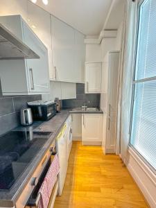 cocina con armarios blancos y suelo de madera en Gower street residences en Londres