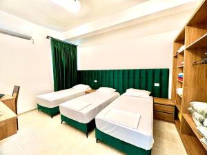 Habitación con 2 camas y pared verde. en Mili apartments, en Berat