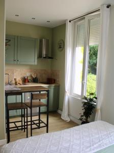 een keuken met groene kasten en een tafel en een raam bij BEAU STUDIO DANS VILLA DE CHARME in Saint-Laurent-de-Brévedent