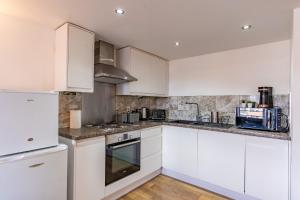a white kitchen with white cabinets and appliances at City Apartment - Free Underground Parking in Birmingham