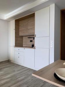 a kitchen with white cabinets and a wooden floor at Hideaway Tenerife Holiday Apartment Las Américas in Playa Fañabe