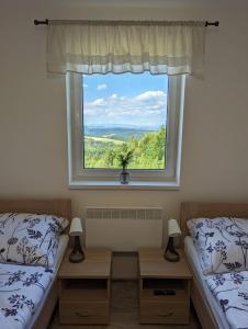 a bedroom with two beds and a large window at Restaurace a penzion Gansberg in Cotkytle