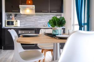 a kitchen with a wooden table and white chairs at L'Eden Urbain・Stationnement Facile・Proche Centre in Châteauroux +18 photos