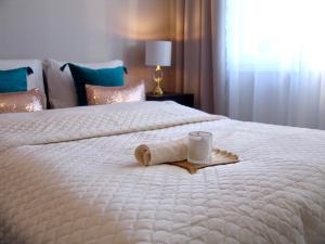 Una cama blanca con una toalla y una vela. en ZB Apartment BEIGE Piekary Śląskie, en Piekary Śląskie