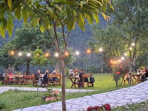 un grupo de personas sentadas en mesas en un parque por la noche en Villa Gjeçaj Guesthouse and Restaurant, en Theth