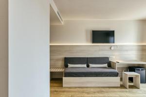 a room with a couch and a tv on a wall at Hotel Emporium - Adults Only in Castelló d'Empúries