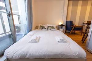 a large white bed with two towels on it at H2H Tsutenkaku in Osaka