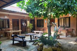 a courtyard with a tree and benches and tables at Tenzai Homestay in Puerto Princesa City