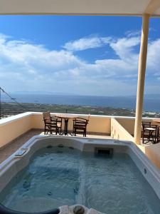 a hot tub on a balcony with a table and chairs at Panorama Oia Apartments in Oia