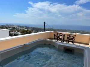 a hot tub on a balcony with a table and chairs at Panorama Oia Apartments in Oia