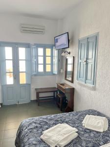 a bedroom with a bed and a desk and windows at Panorama Oia Apartments in Oia