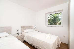 扎波里斯的住宿－Rimagis Apartments，一间白色卧室,配有两张床和窗户
