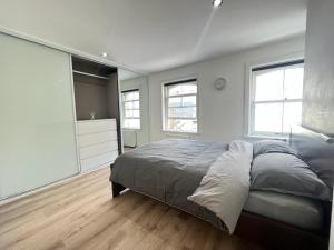 a bedroom with a large bed and two windows at Full Apartment! Brick Lane! in London