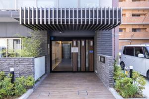 a walkway leading to a building with a revolving door at H2H Tsutenkaku in Osaka