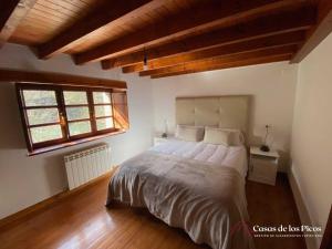 a bedroom with a large bed in a room with wooden ceilings at Vivienda vacacional El Cau - Casas de Los Picos in Ruenes