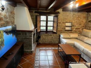- un salon avec un canapé et une télévision à grand écran dans l'établissement Vivienda vacacional El Cau - Casas de Los Picos, à Ruenes
