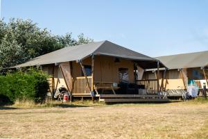 a large tent with a porch in a field at Glamping Ameland in Buren