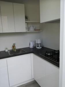 uma cozinha branca com armários brancos e um lavatório em De Zeemeeuw em Egmond aan den Hoef